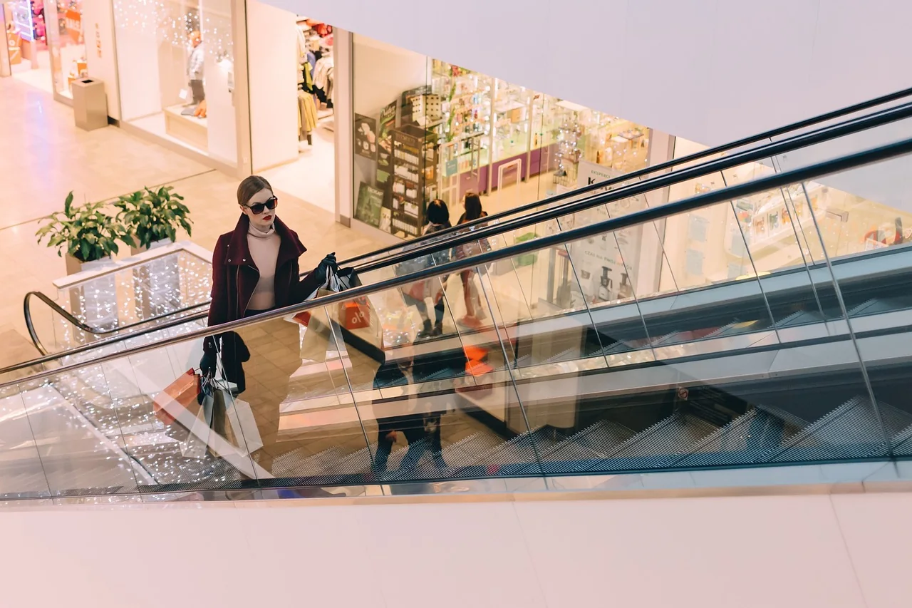 Shoppers carrying paper shopping bags through a bright shopping centre