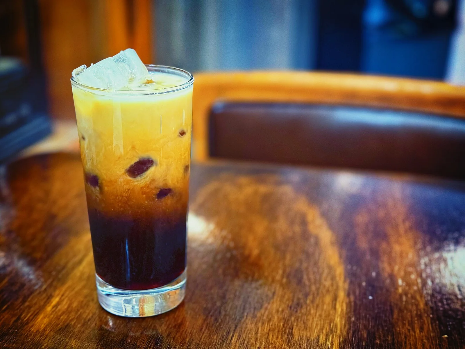 Iced coffee with ice cubes in a tall glass on a café table