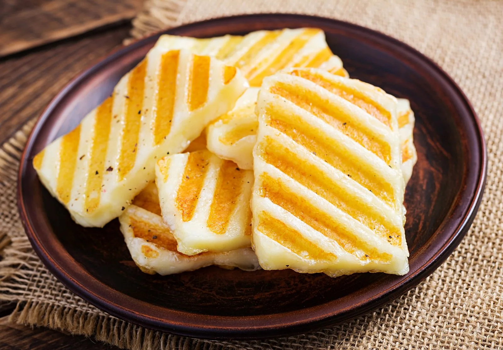 Grilled halloumi cheese on a plate on a wooden background