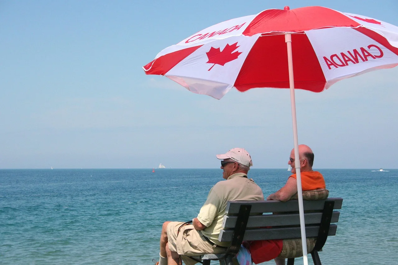 Retired couple sitting together on a seafront bench looking out over a calm Mediterranean sea
