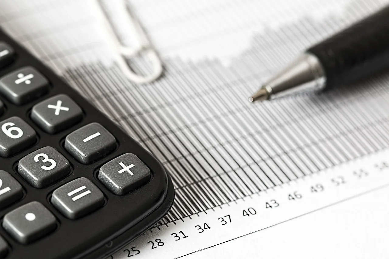 Accountant going through tax paperwork with a calculator and laptop on an office desk