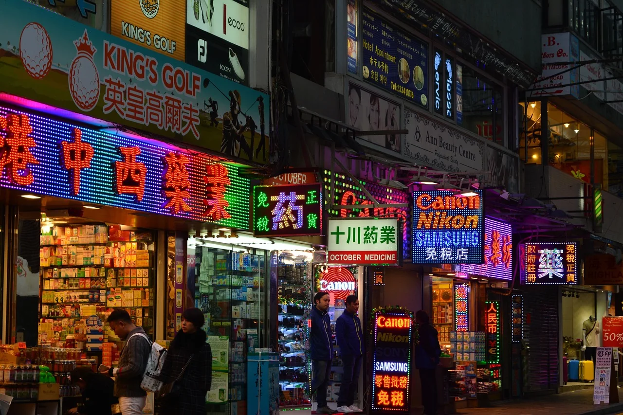Illuminated green pharmacy cross sign on a street at night
