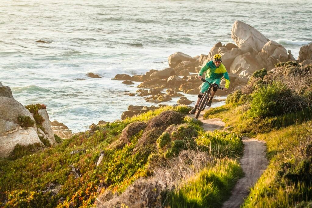 Mountain biker riding a trail along the coast at sunset